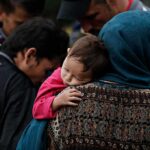 Prosecution-First Plan Targeted Kids, Memo Shows Mother holding a sleeping child on her shoulder