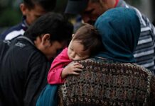 Prosecution-First Plan Targeted Kids, Memo Shows Mother holding a sleeping child on her shoulder