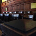 Lawmen Stunned — Quiet Release Sparks Fury Empty wooden jury box with numbered chairs