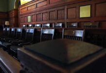 Lawmen Stunned — Quiet Release Sparks Fury Empty wooden jury box with numbered chairs