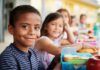 Smiling boy at a lunch table with classmates