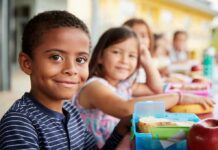 Smiling boy at a lunch table with classmates