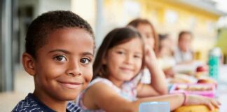 Smiling boy at a lunch table with classmates