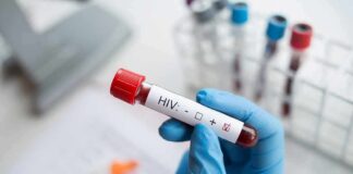 Gloved hand holding a blood sample tube labeled for HIV test