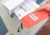 Hand dropping mail-in ballots into a drop box