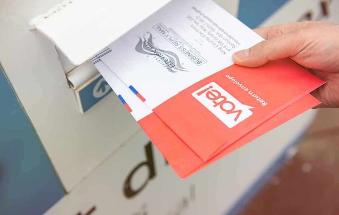shutterstock_1671839167 Hand dropping mail-in ballots into a drop box