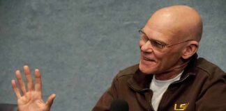 Bald man speaking into a handheld microphone