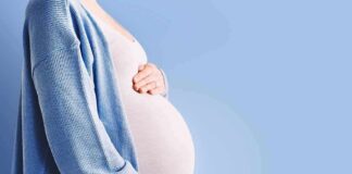 Pregnant person holding belly in blue cardigan