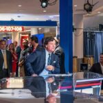 Angel Studios Cornered—Carlson Fallout News anchor at a studio desk with crowd and cameras in background