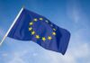 EU Migration Alarms Flashing Red European Union flag waving against blue sky