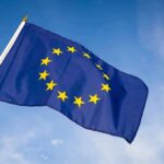 EU Migration Alarms Flashing Red European Union flag waving against blue sky