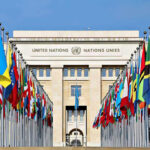 Trump Rejects Arrest Threat Against Netanyahu United Nations building with numerous national flags outside.