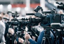 Record T. rex Sale Sparks Ownership War Broadcast cameras on tripods at a press event