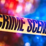 Crime scene tape with blurred emergency lights in background