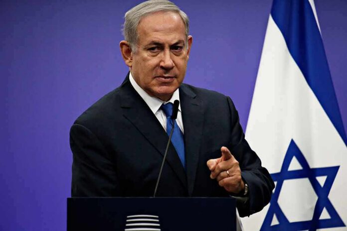 shutterstock_1042782061 man in suit speaking at a podium with an Israeli flag
