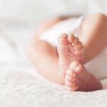 Hormone Surge In A Baby? Doctors Move baby feet on a soft white blanket
