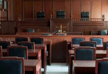 Doxing Frenzy Triggers Rare Court Lockdown Empty courtroom with wooden benches and judge's bench