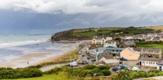 Coastal village by a wide sandy beach under cloudy skies
