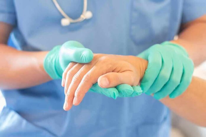 shutterstock_1175545846 Healthcare worker in gloves holding a patient's hand