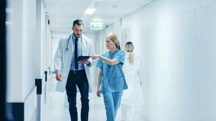 Doctors walking in a hospital corridor reviewing a tablet