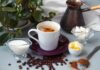 Cup of coffee with milk, butter, and spices on a table
