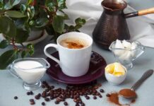 Cup of coffee with milk, butter, and spices on a table