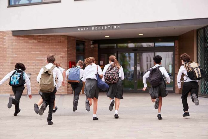 shutterstock_1195675999 Students in uniforms running toward a school entrance