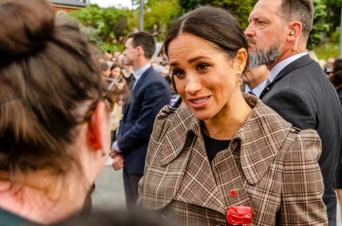 woman in plaid coat speaking to a person in a crowd