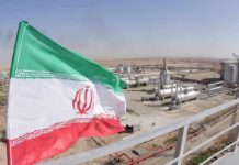 War Map Redrawn? Tehran Dares Washington Iran flag over an oil and gas facility in a desert landscape