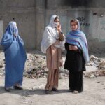 Abduction Pipeline Exposed in Pakistan Three women in traditional attire standing in an urban setting with debris in the background