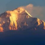 Himalayan Collapse Sparks Awkward Climate Truth Snow-capped mountain peak glowing at sunrise