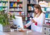 Pharmacist checking medication box at computer counter
