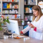 Pharmacy Experiment Just Got Much Bigger Pharmacist checking medication box at computer counter