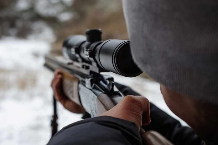 shutterstock_1666619383 person aiming a rifle with a scope outdoors