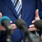 LeBron ‘Racist’? Trump Sparks Fresh Firestorm Speaker in blue suit gesturing behind microphones