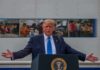 Donald Trump speaks at a podium with arms outstretched