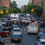 Police vehicles and officers block a city street during an active scene