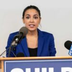Commissioner Quits Amid Clark Uproar Woman in blue blazer speaking at a press conference podium