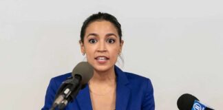 Woman in blue blazer speaking at a press conference podium