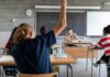 Student raising hand in classroom during lesson