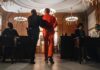 Ohio Court Melee: Throat Punch, Bones Broken Prisoner in orange jumpsuit escorted by officer in a courtroom