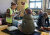 Volunteers assist people resting on mats in a temporary shelter
