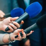 Teachers’ Union Boss Comes Unhinged at Convention Reporters holding colorful microphones