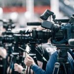 Dark-Web Tip, No Action—Disaster Follows Broadcast cameras on tripods at a press event