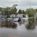 Torrents Paralyze Capital – Shelters Overflow Flooded residential street with partially submerged cars