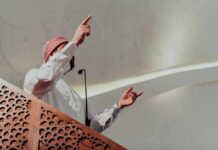 Mayor’s Ramadan Push Sparks Constitutional Fight Speaker in traditional attire gesturing from a carved wooden podium