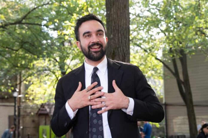 man in a suit speaking outdoors with hands on chest