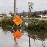Flooded rural road with water over roadway sign