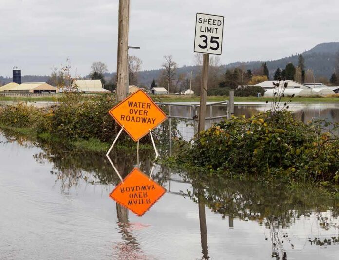 Flooded rural road with water over roadway sign