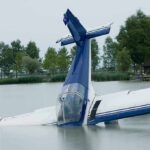 Plane Crash Downplayed? Posts Disappear A submerged airplane partially in a lake with trees in the background